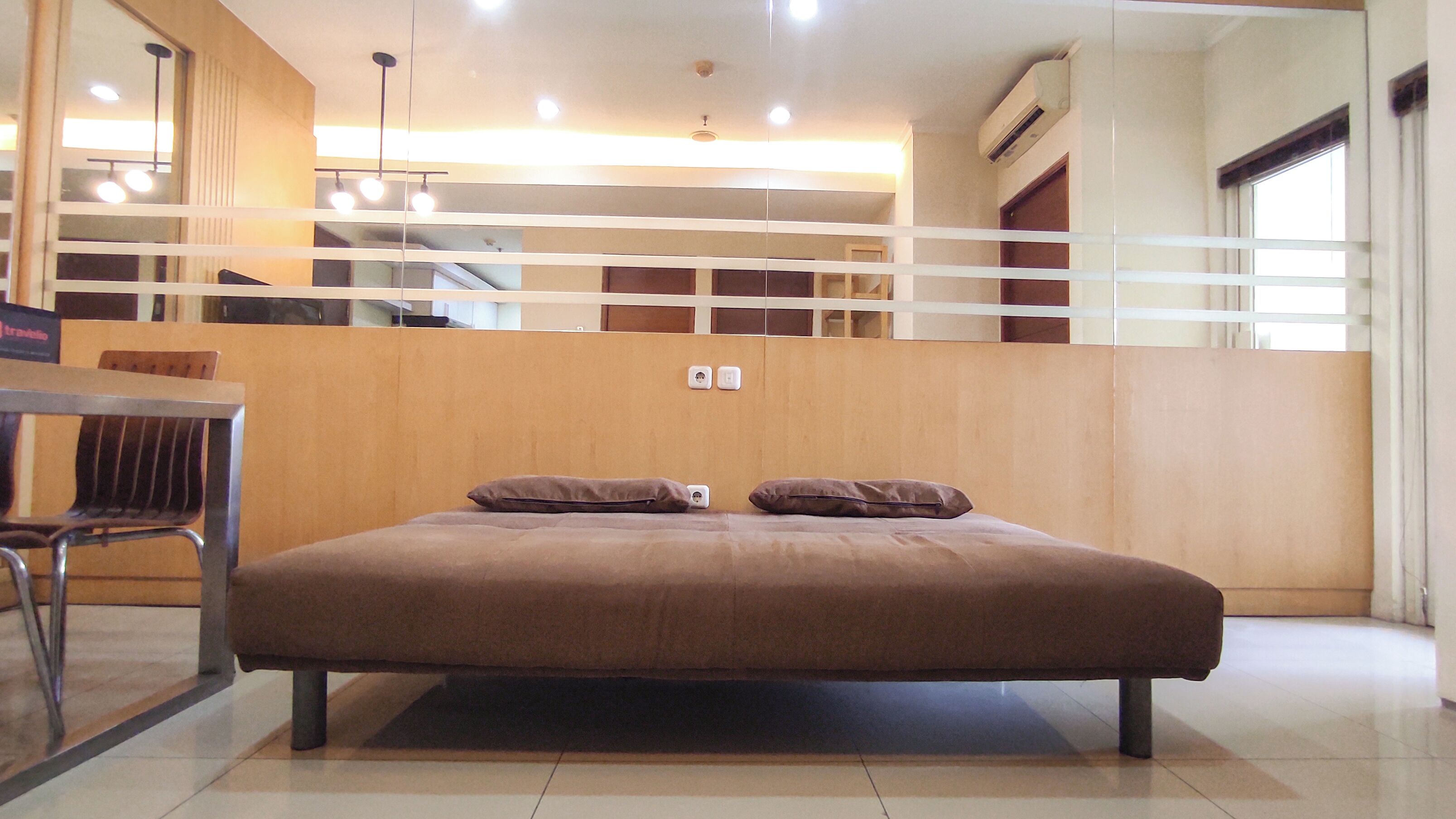 A modern hotel room with a large bed, a wooden headboard, and a small table with a chair.