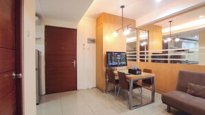 A compact room with a wooden door, a small table with chairs, a television, and a sofa. - Good Place and Tidy 2BR at High Point Serviced Apartment (Surabaya)
