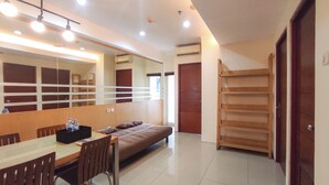 A hotel room with a bed, a desk with chairs, a large mirror, and a wardrobe. - Good Place and Tidy 2BR at High Point Serviced Apartment (Surabaya)