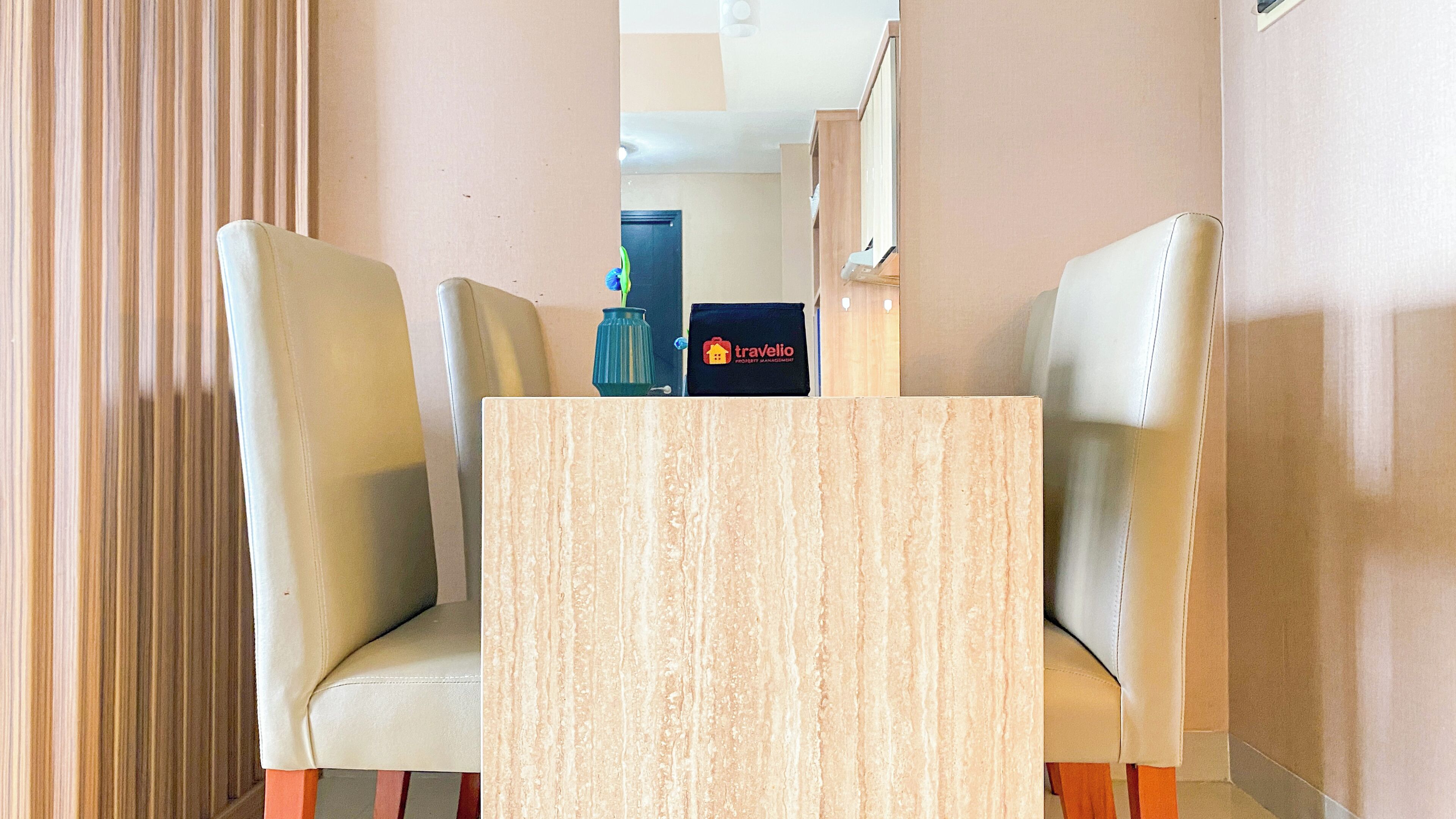 Habitación de hotel con una mesa de madera y dos sillas de cuero. Se ve un cartel de travelio en la pared.