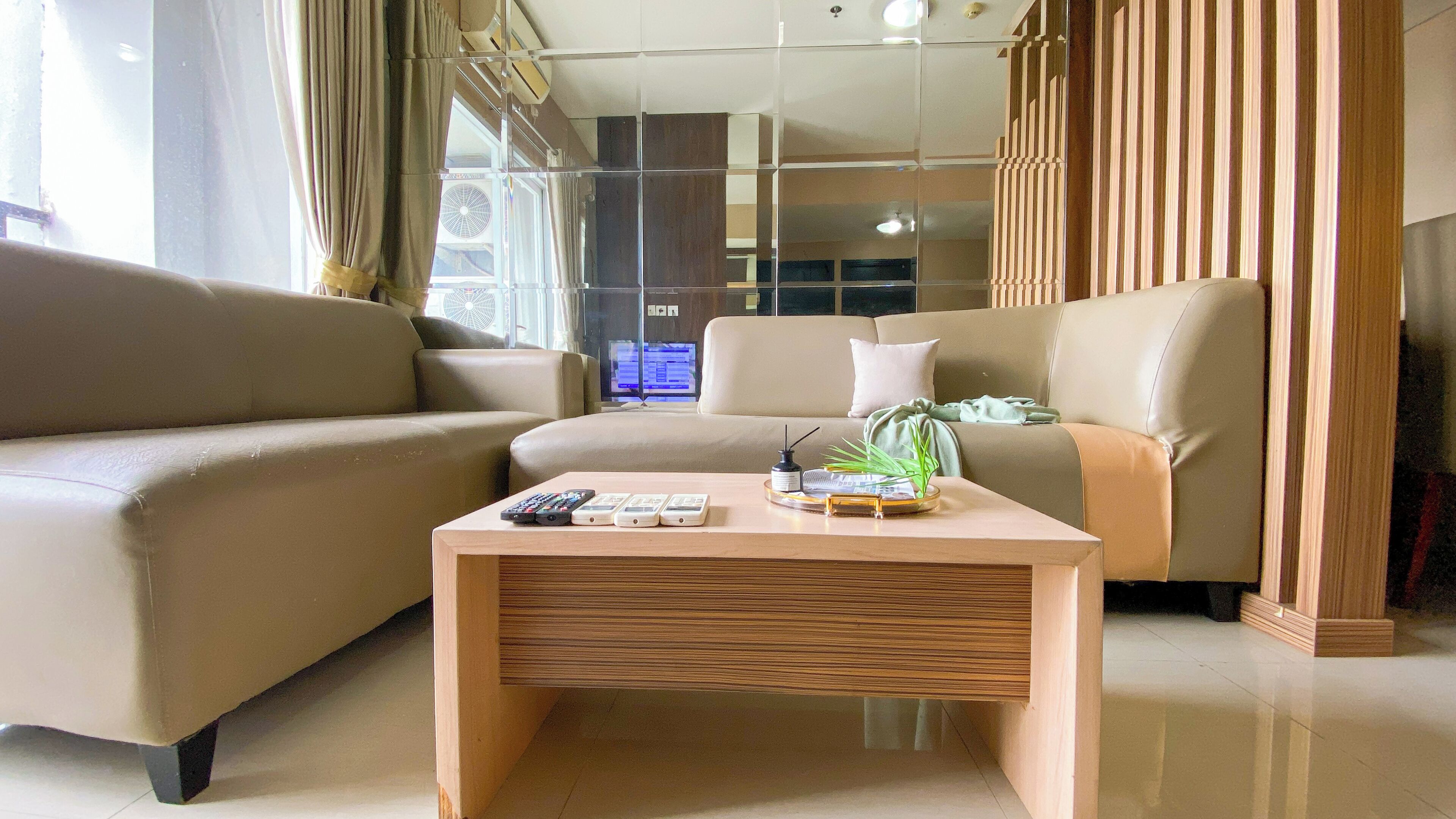 A modern living room with a beige sofa, a wooden coffee table, and a television in the background.