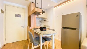 Una cocina compacta con refrigerador incorporado, una pequeña mesa de comedor y una silla.