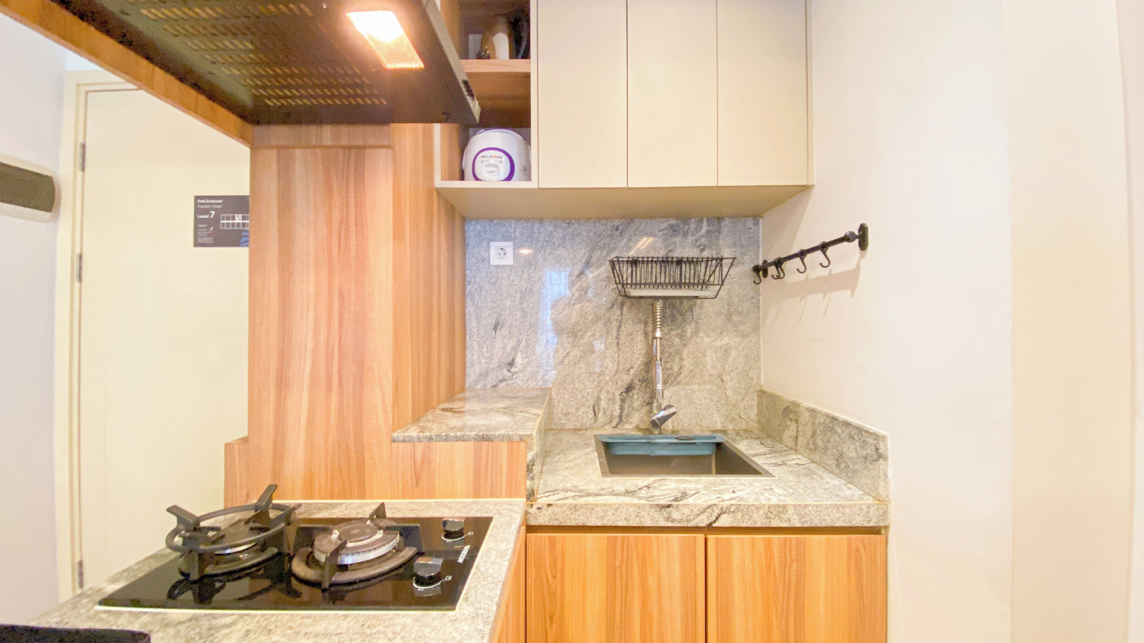 A compact kitchen with a gas stove, wooden cabinets, and a marble countertop.