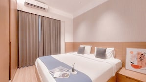 A hotel room with a bed, a bedside table, a nightstand, a window with curtains, and an air conditioning unit. - Spacious and Good Deal 3BR Sky House BSD Apartment (Pagedangan)