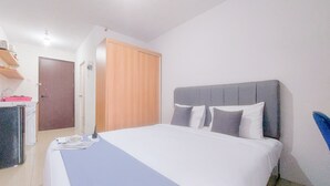 A bedroom with a bed, a wardrobe, and a desk with a chair. - Good and Homey Studio Apartment at Sudimara Forestwalk (South Tangerang)