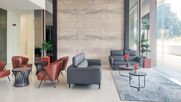 A modern lobby with leather sofas, a coffee table, and potted plants. - Good and Homey Studio Apartment at Sudimara Forestwalk (South Tangerang)