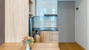 Une cuisine compacte dotée d’un réfrigérateur encastré, de meubles de rangement en bois et d’une petite table agrémentée d’un vase de fleurs.