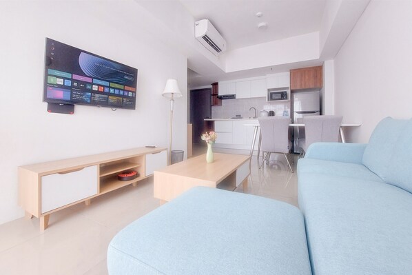 Una sala de estar moderna con un sofá azul claro, un mueble de televisión de madera y un televisor de pantalla plana montado en la pared.