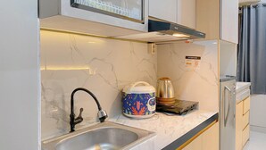 Uma cozinha moderna com uma pia de aço inoxidável, uma cafeteira e uma chaleira sobre a bancada.