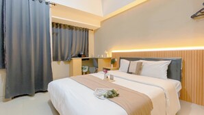 Quarto de hotel com duas camas, cabeceira de madeira, mesa de cabeceira com abajur e janela com cortinas.