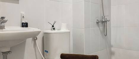 A bathroom with a white sink, toilet, and shower.