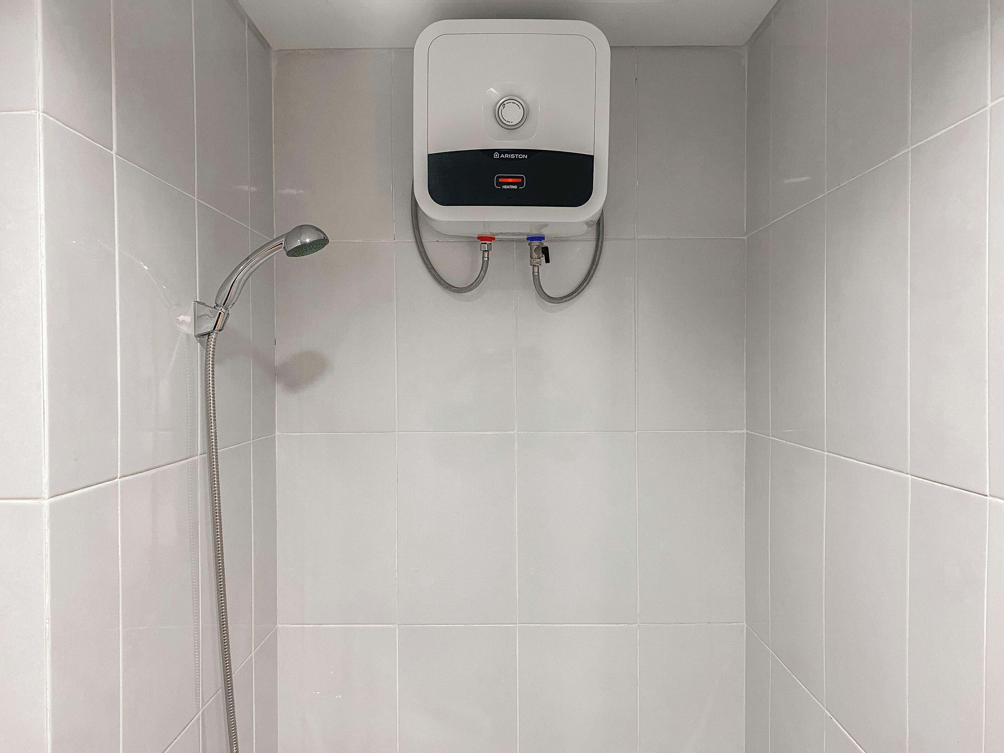 A shower area with a wall-mounted heater and a handheld showerhead.