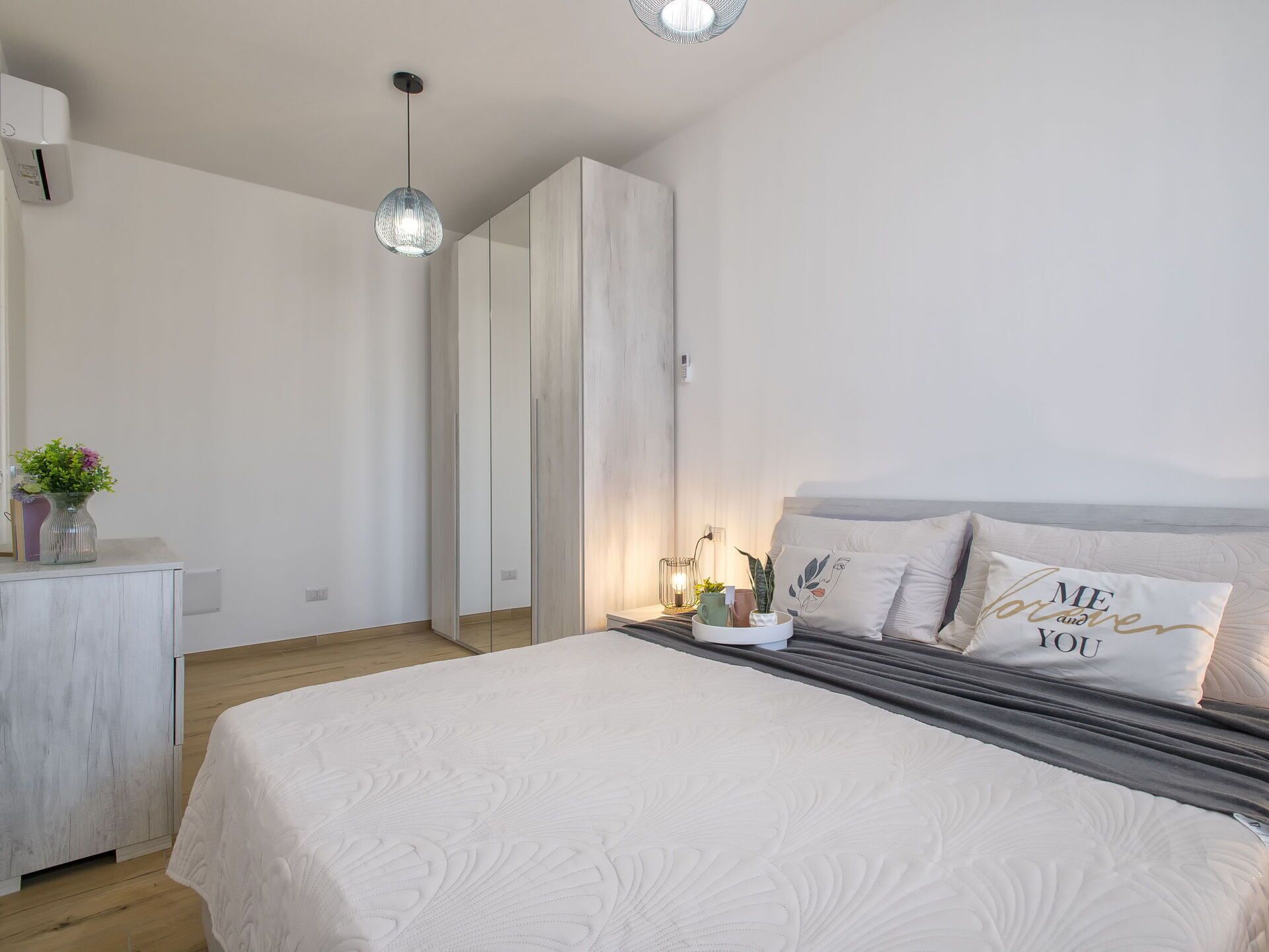 A bedroom with a bed, bedside table, and a hanging light fixture.