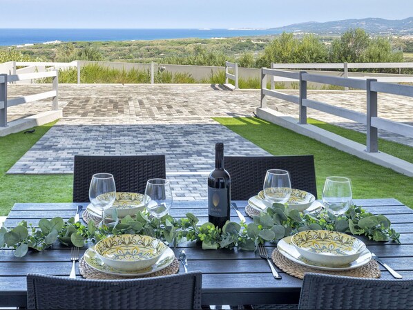 Una mesa lista para una comida con una botella de vino, con vistas a un paisaje pintoresco.