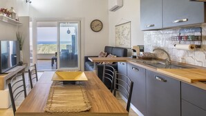 A modern kitchen with a wooden dining table, grey cabinets, and a view of the outdoors. - Nice apartment for 5 people with WIFI, A/C, TV and patio (Valledoria)