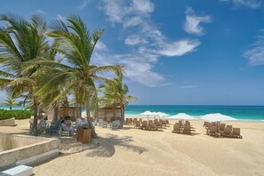 Een strandresort met palmbomen, ligbedden en parasols.