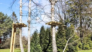 Uma estrutura de madeira com design geométrico, cercada por árvores e grama.