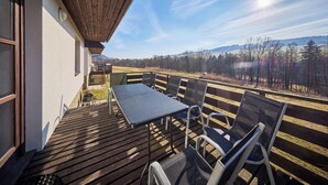 Une terrasse en bois avec une table et des chaises, offrant une vue sur un paysage magnifique.