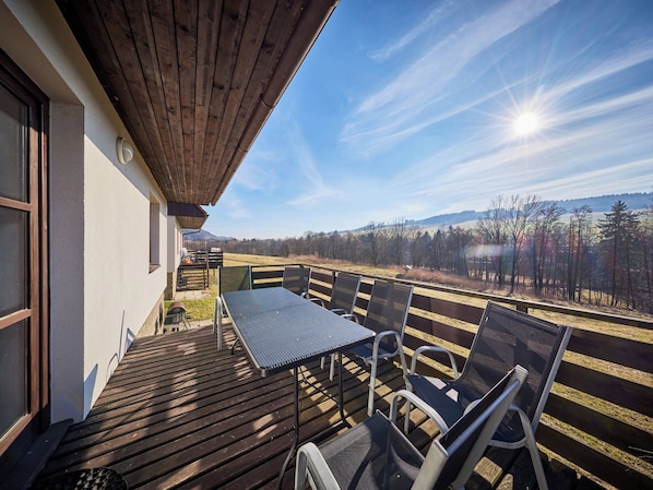 Une terrasse en bois avec une table et des chaises, offrant une vue sur un paysage magnifique.