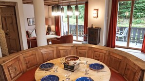 A round wooden table with blue plates and silverware, surrounded by red cushioned benches.