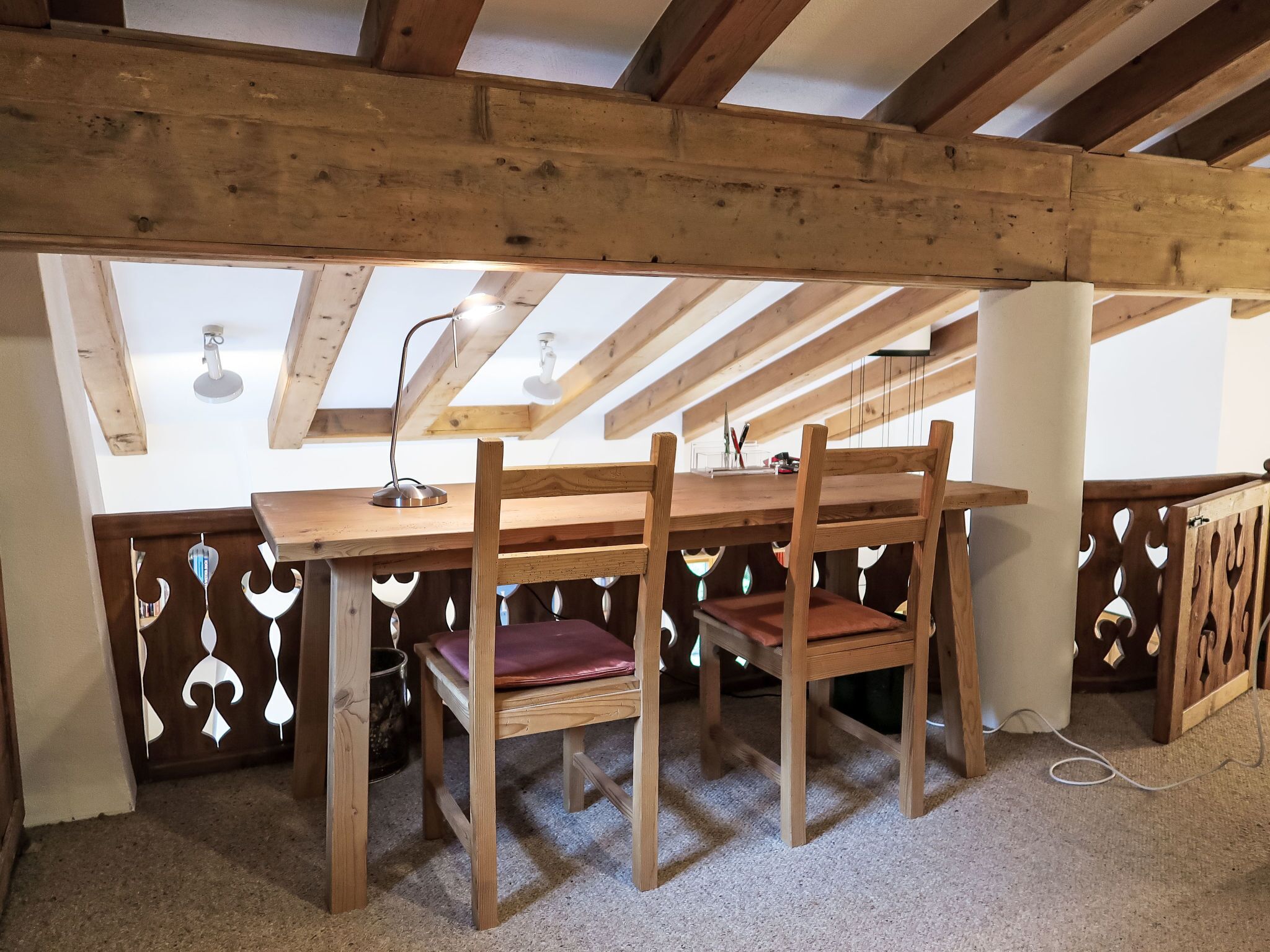 Une table à manger en bois avec des chaises, un ventilateur de plafond et une fenêtre donnant sur le ciel.