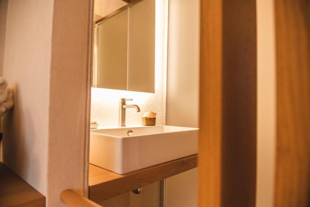A bathroom with a white sink, a mirror, and a wooden counter.