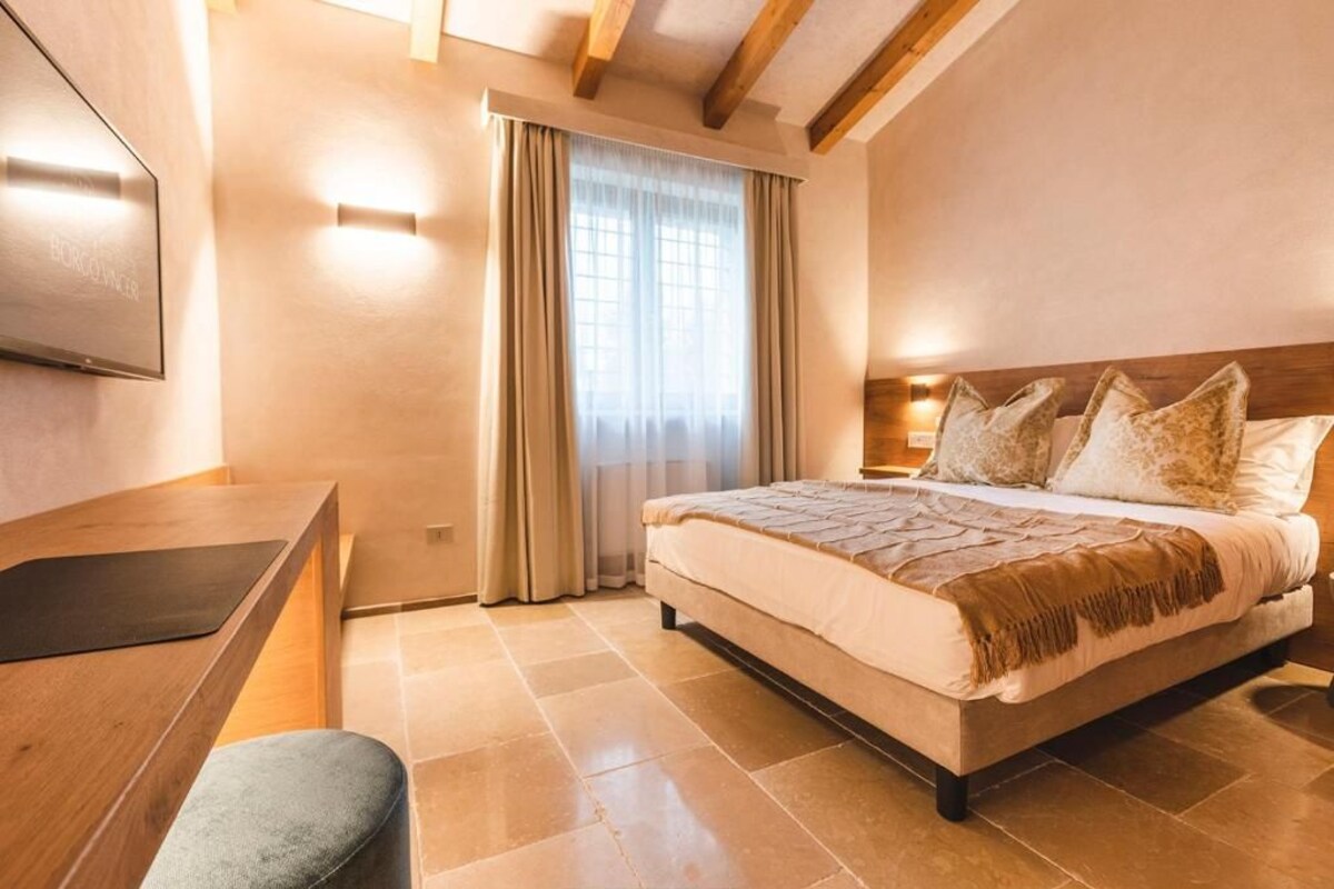 A bedroom with a bed, a desk, and a chair.