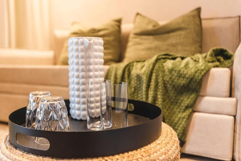 Un plateau avec des verres et un vase blanc à texture sur un tapis tissé.