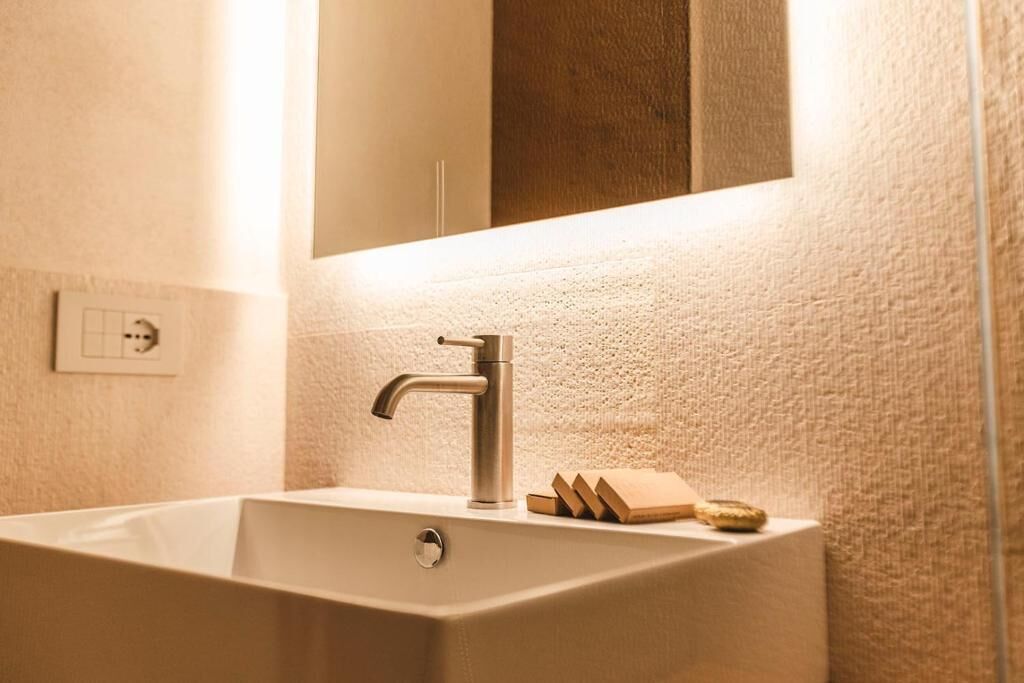 A bathroom with a rectangular sink, a modern faucet, and a mirror above it.