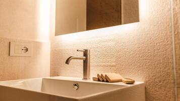 A bathroom with a rectangular sink, a modern faucet, and a mirror above it.