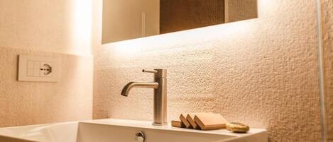 A bathroom with a rectangular sink, a modern faucet, and a mirror above it.