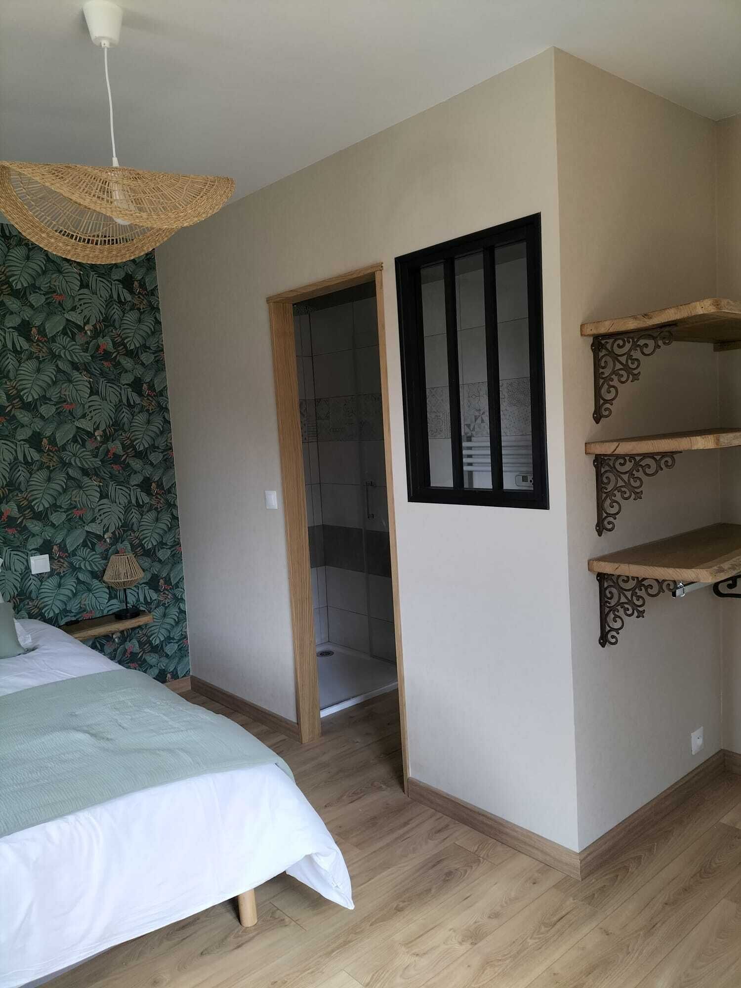 A bedroom with a bed, a hanging light fixture, a shower, and built-in shelves.