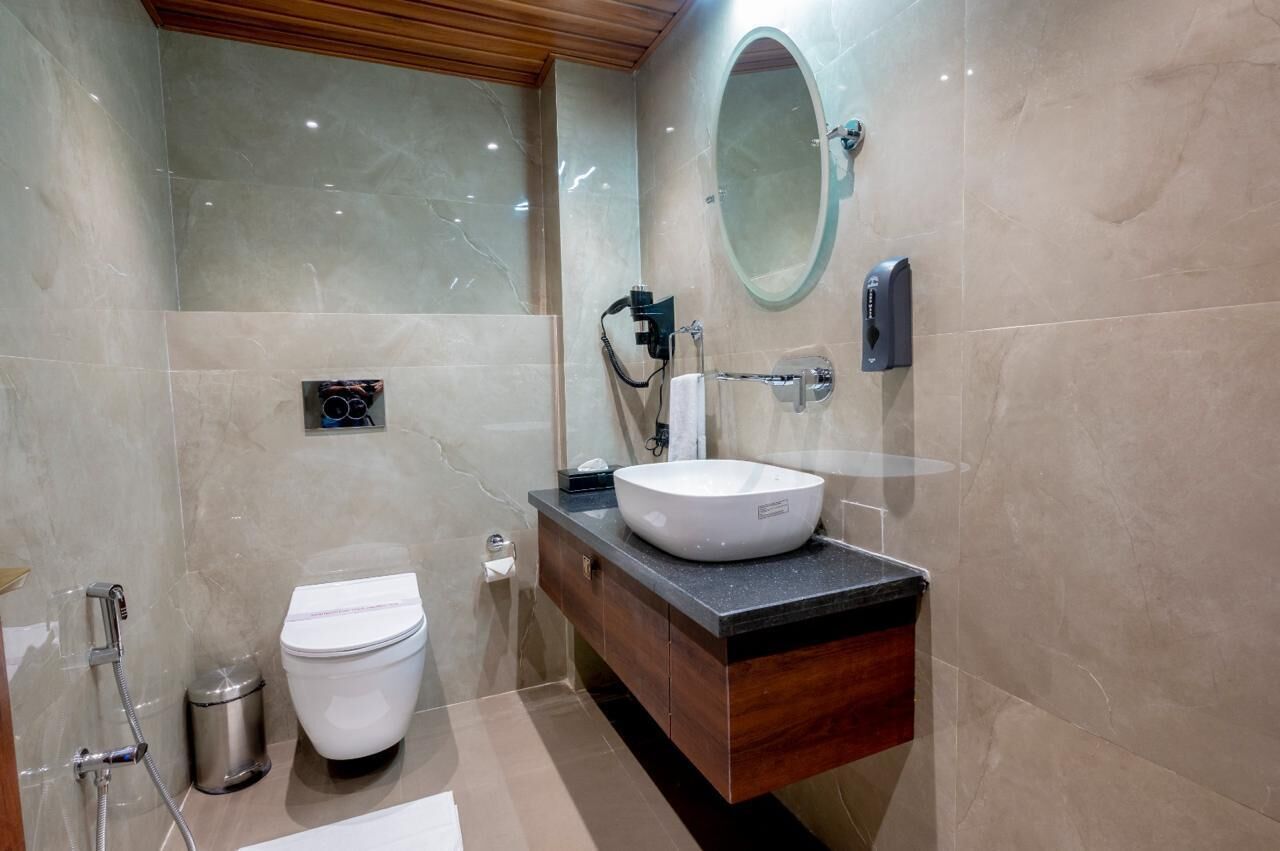 A modern bathroom with a white toilet, a round sink, and a mirror.