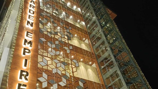 Un edificio alto dal design moderno, con un cartello ben visibile che riporta la scritta "GARDEN EMPIRE".