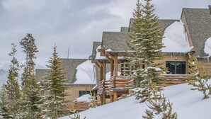 Eine Lodge mit Holzfassade und schneebedeckten Dächern, umgeben von schneehohen Bäumen.