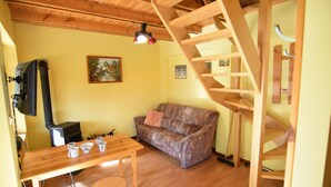 A cozy room with a wooden table, a sofa, a staircase, and a fireplace. - Holiday Home near Lake Mausz, Kashubia (Parchowo)