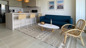 A modern living space with a kitchen, a blue sofa, and a dining area with wicker chairs. - w*| Prestigious 2BR w/ Amazing View in Morros Eos (Cartagena de Indias)