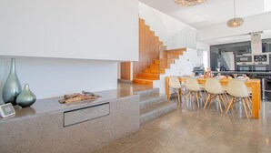A modern kitchen with a central island, a dining area with chairs, and a staircase with wooden steps. - Casa Madeira - Stunning Villa in Carvoeiro (Carvoeiro)