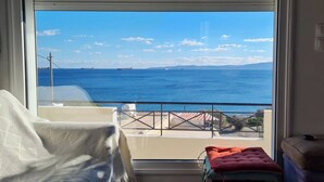 Un balcon avec vue sur la mer, une chaise et une petite table avec un coussin.