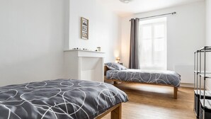 A modern bedroom with two beds, a white wardrobe, a bedside table with a lamp, and a window with curtains. - Renovated house with wifi, in the heart of St Mars la Jaille (Vallons-de-L'Erdre)