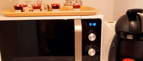 A Samsung microwave with a digital clock displaying 9:18, a coffee maker, and a tray with jars of condiments.