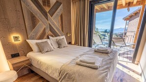 Een slaapkamer met een groot bed, houten wanden, een nachtkastje en uitzicht op het omliggende landschap.
