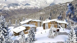 Een bergresort bedekt met sneeuw, met chalets, skipistes en een achtergrond van besneeuwde toppen.