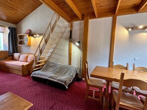 A cozy room with a wooden ceiling, a bed, a desk, and a chair.