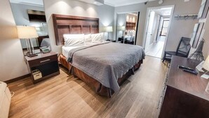 Moderni hotellihuone, jossa on suuri sänky, yöpöydät, työpöytä ja peili.