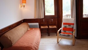 Una habitación acogedora con un banco de madera, un sofá con cojines y una silla con un cojín estampado.