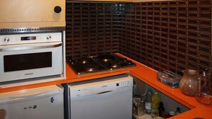 Una cocina compacta con horno Samsung, lavavajillas Bosch y salpicadero de azulejos negros.