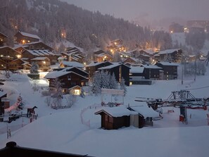 A snow-covered village with wooden buildings and ski lifts.