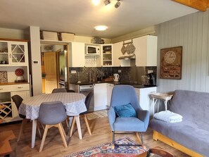 A compact living space with a dining area, a sofa, a coffee table, and a kitchenette.