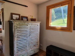 Um armário de madeira rústico com uma janela acima, um banco e uma porta que dá para outro cômodo.